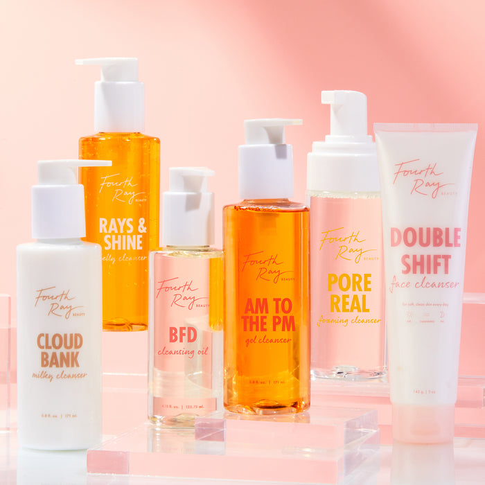 BFD Oil Cleanser face cleanser by Fourth Ray Beauty standing with a white pump and pale golden oil, displayed among companion cleansers on clear acrylic risers against a soft pink gradient; ColourPop skincare product shot.