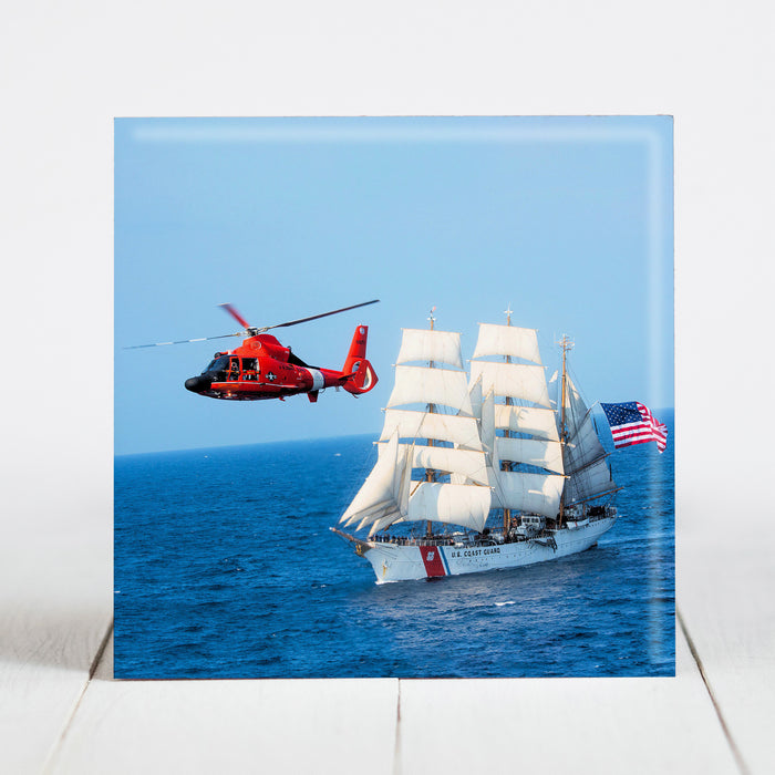 Coast Guard MH-65 Dolphin Helicopter flies above the Training Cutter, Eagle