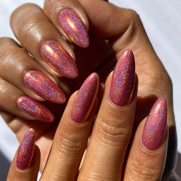 Close-up of nails painted with Flamin' Hot Holo Nail Lacquer on medium skin tone.