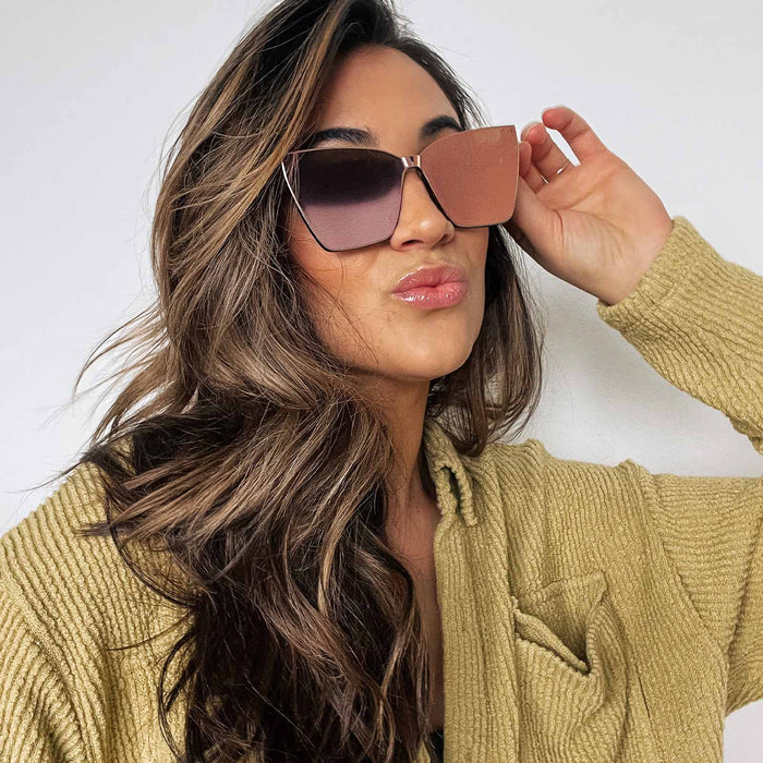 lifestyle - female wearing diff eyewear goldie cat eye sunglasses with a apricot crystal frame and peach mirror lenses front view