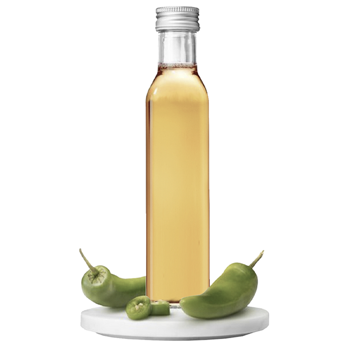 A bottle of Jalapeño Vinegar with whole green jalapeños displayed in front of it.