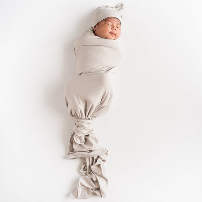 Sleeping newborn wearing Knotted Cap in Oat with matching swaddle blanket