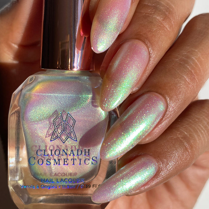 Close-up of nails painted with Lucidum Nail Lacquer on medium skin tone. Hand is holding polish bottle.