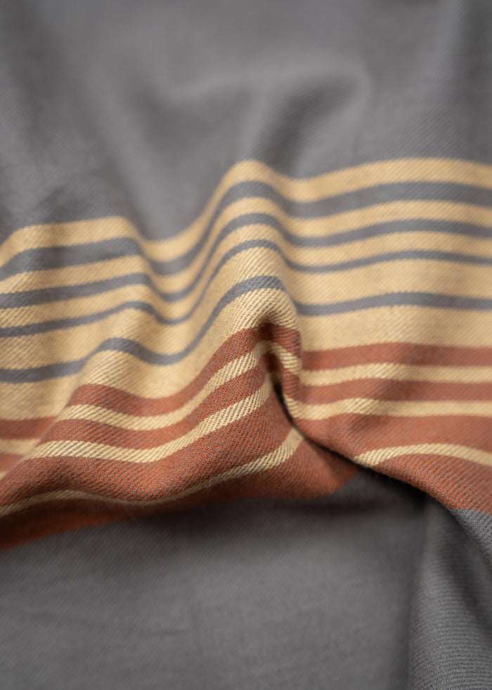 Gray fabric with orange and beige stripes, gently folded, creating a soft, flowing texture.