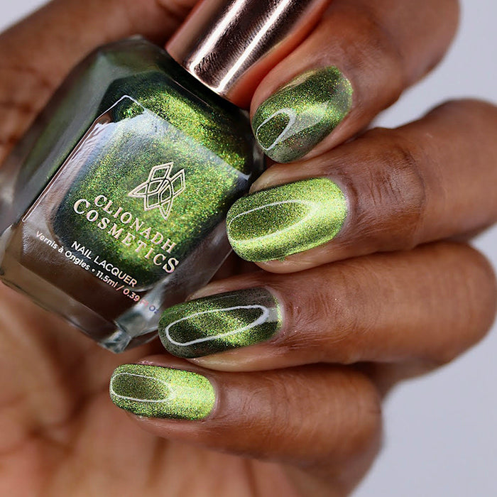 Close-up of nails painted with Velvet Verdigris Nail Lacquer on deep skin tone. Hand is holding polish bottle.
