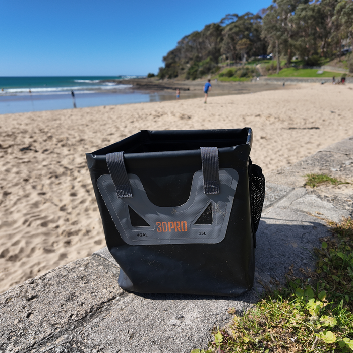 15L/4GAL Pro Square Folding Bucket with '3DPRO' branding on a stone ledge at a beach.
