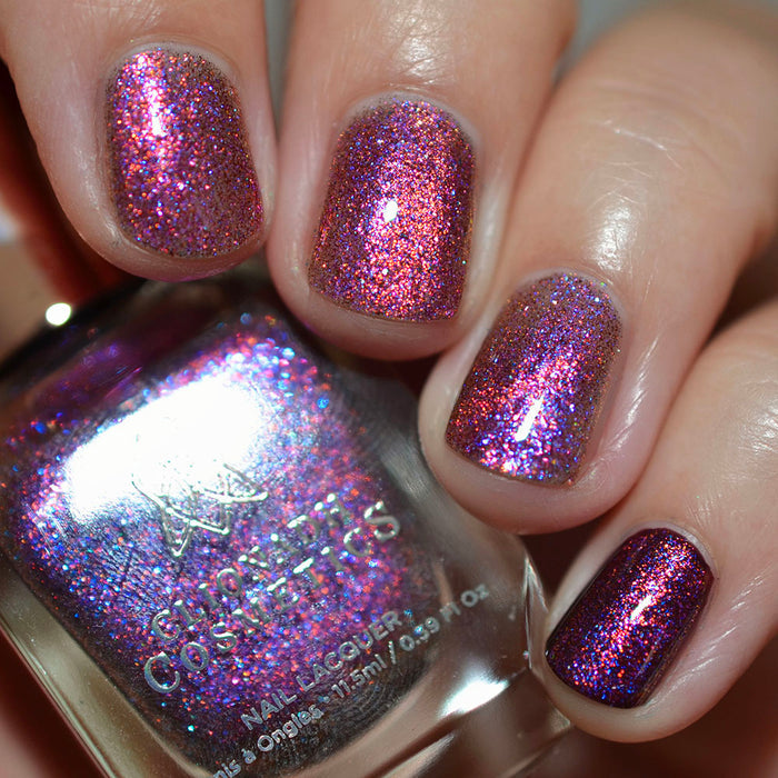 Close-up of nails painted with Amorem Nail Lacquer on fair skin tone. Hand is holding polish bottle.