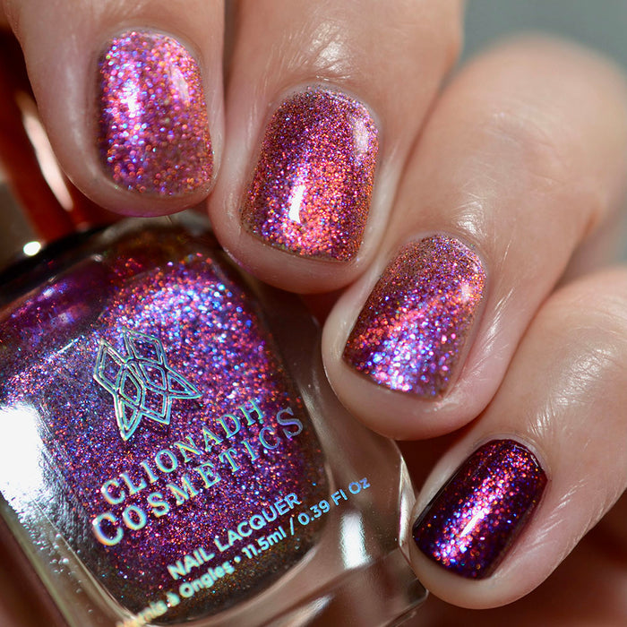 Close-up of nails painted with Amorem Nail Lacquer on fair skin tone. Hand is holding polish bottle.