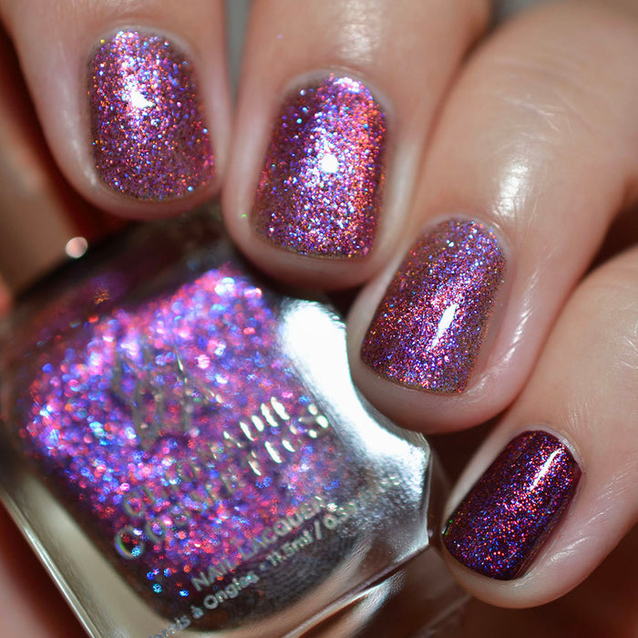 Close-up of nails painted with Amorem Nail Lacquer on fair skin tone. Hand is holding polish bottle.