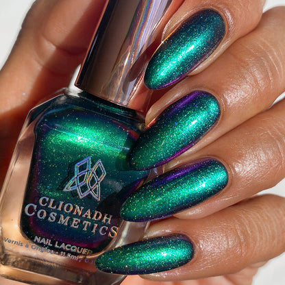 Close-up of nails painted with Anneal Nail Lacquer on medium skin tone. Hand is holding polish bottle.