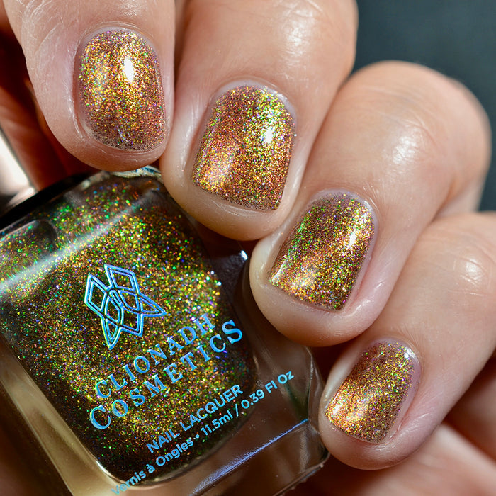 Close-up of nails painted with Apple Picking Nail Lacquer on fair skin tone. Hand is holding polish bottle.