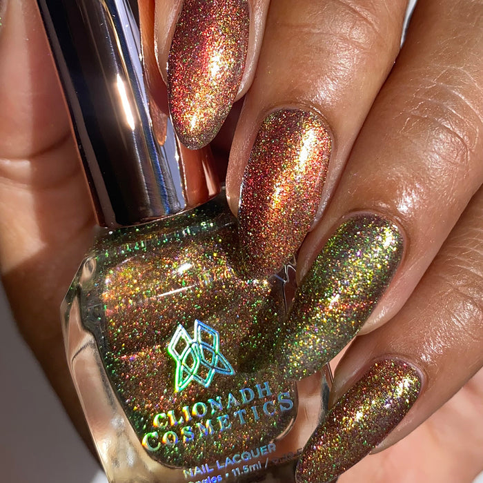 Close-up of nails painted with Apple Picking Nail Lacquer on medium skin tone. Hand is holding polish bottle.