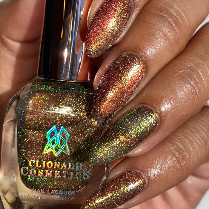 Close-up of nails painted with Apple Picking Nail Lacquer on medium skin tone. Hand is holding polish bottle.