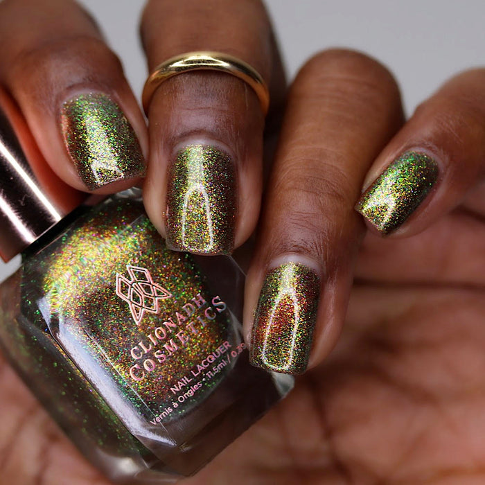 Close-up of nails painted with Apple Picking Nail Lacquer on deep skin tone. Hand is holding polish bottle.