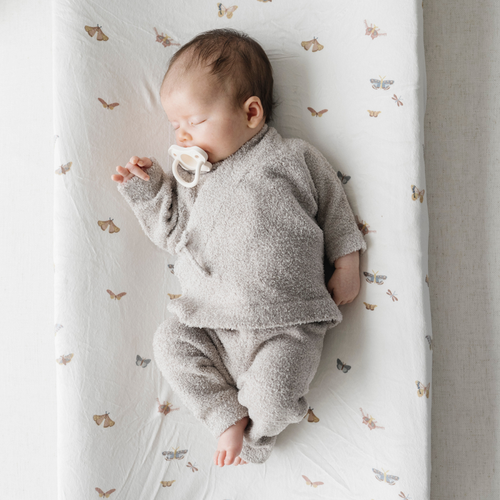Baby girl sleeps wearing taupe bamboni lite outfit.