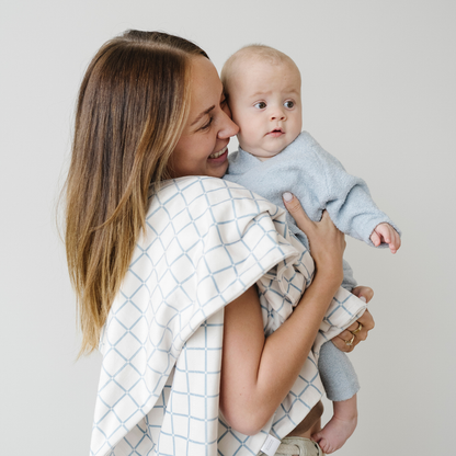 Mom holding baby boy wearing a light blue bamboni lite outfit.