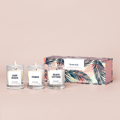 Three mini candles labeled "Beach Cottage", "Hawaii", and "Surf Shack" in front of a box on a cream background