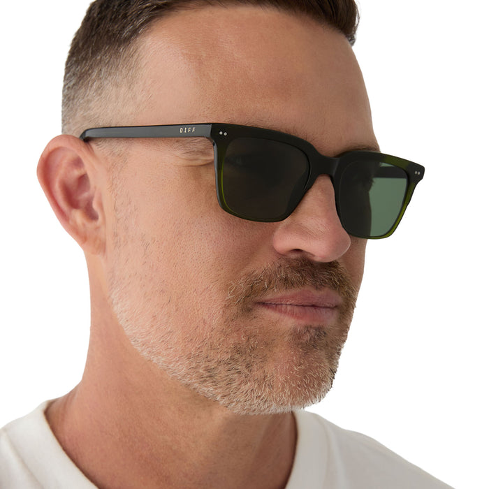 on model - male wearing diff eyewear featuring the billie square sunglasses with a dark olive green crystal frame and g15 polarized lenses angled view