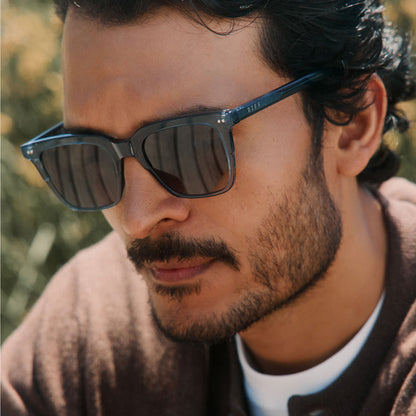 lifestyle - male outdoors wearing diff eyewear billie square sunglasses in night sky blue frame with grey polarized lens angled view