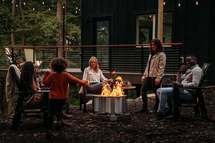 A group of friends gathered around the fire with a Breeo X Series Firepit and Base.