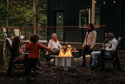 A group of friends gathered around the fire with a Breeo X Series Firepit and Base.