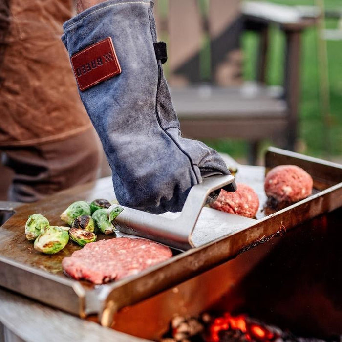 Thisis an image of a man pressing a burger on the Flat top using a Griddle Press