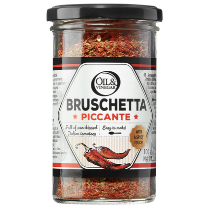 A jar of Bruschetta Piccante dried herb blend, showing the product name and an illustration of a chili pepper, indicating a spicy flavor.