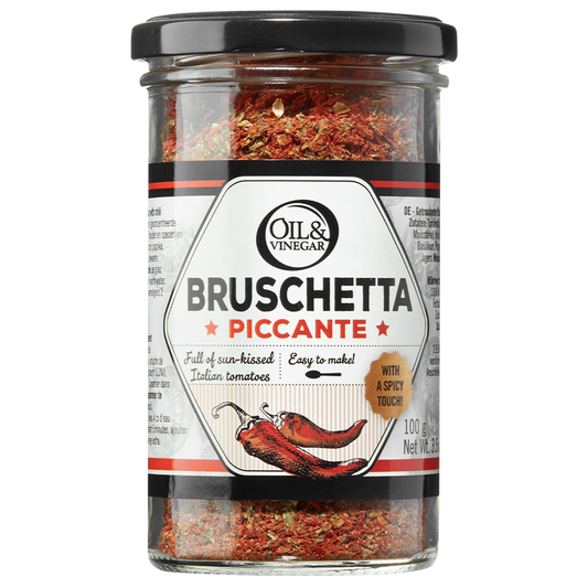 A jar of Bruschetta Piccante dried herb blend, showing the product name and an illustration of a chili pepper, indicating a spicy flavor.