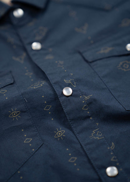 Close-up of a navy shirt with silver buttons, featuring subtle geometric and eye patterns in gold.
