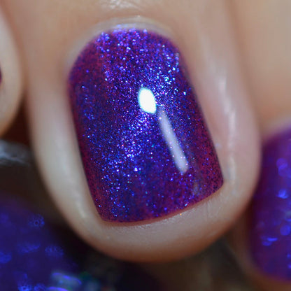 Close-up of one nail painted with Butterfly Pea Flower Nail Lacquer on fair skin tone. Emphasizes blue glitter particles.