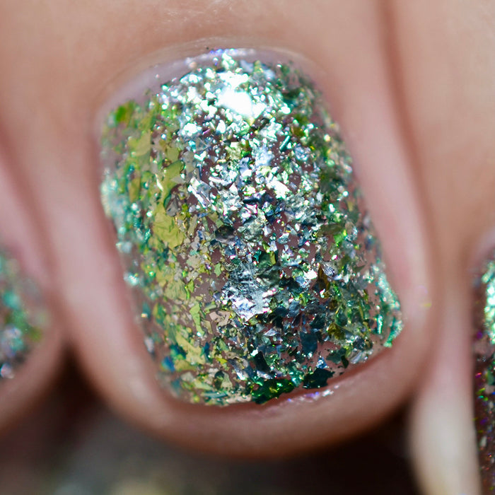 Close-up of one nail painted with Catacomb Nail Lacquer on fair skin tone. Emphasizes chunky silver flakes.