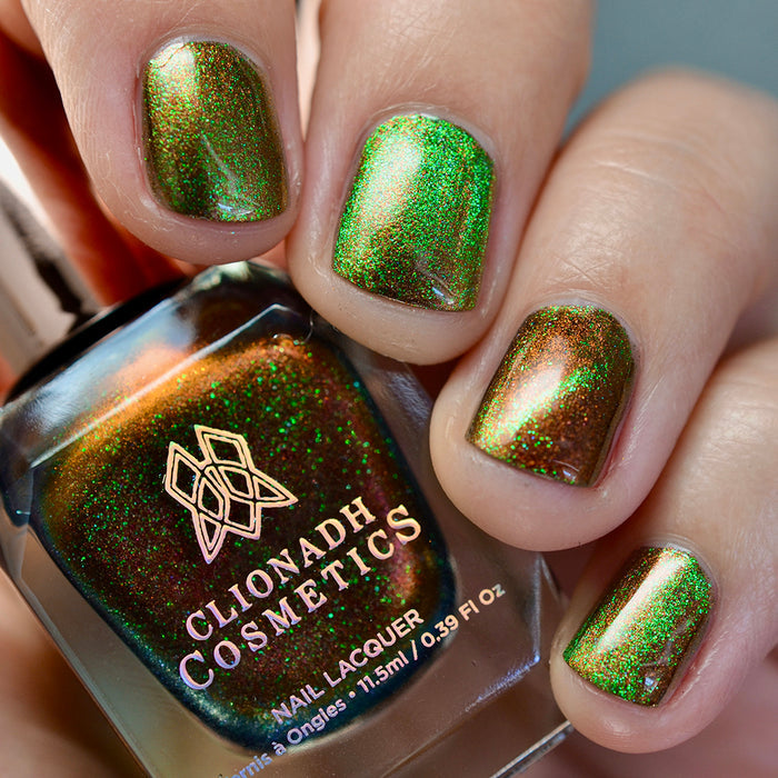 Close-up of nails painted with Cemetery Nail Lacquer on fair skin tone. Hand is holding polish bottle.
