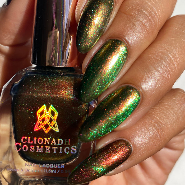 Close up shot of nails done with Cemetery Nail Lacquer on medium skin tone. Hand is holding polish bottle.