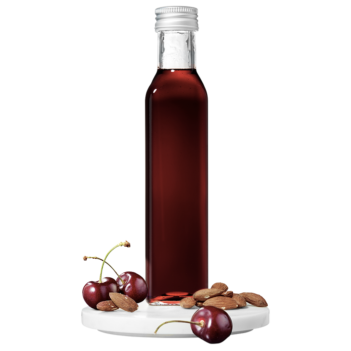 A tall, slender bottle of Cherry Almond Vinegar with a silver cap, accompanied by whole cherries and almonds placed in front.