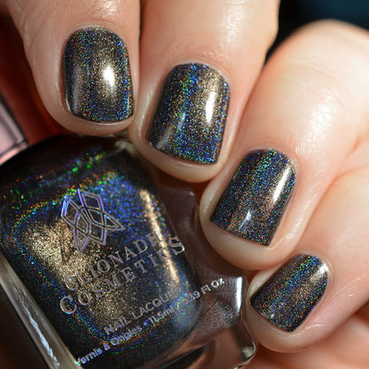 Close-up of nails painted with Chocholo Chips Nail Lacquer on fair skin tone. Hand is holding polish bottle.