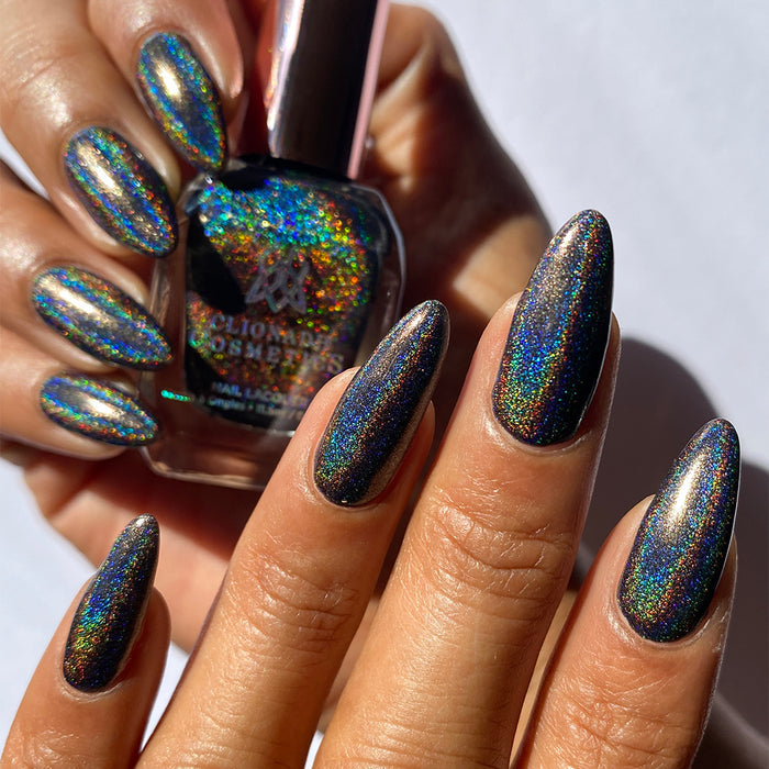 Close-up of nails painted with Chocholo Chips Nail Lacquer on medium skin tone. Hand is holding polish bottle.