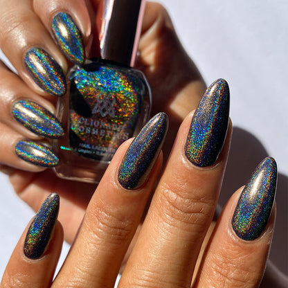 Close-up of nails painted with Chocholo Chips Nail Lacquer on medium skin tone. Hand is holding polish bottle.