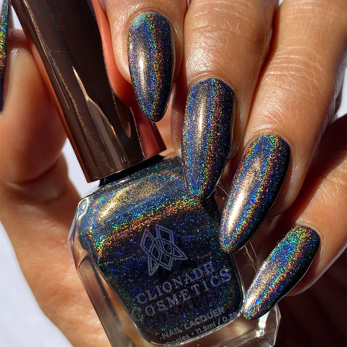 Close-up of nails painted with Chocholo Chips Nail Lacquer on medium skin tone. Hand is holding polish bottle.