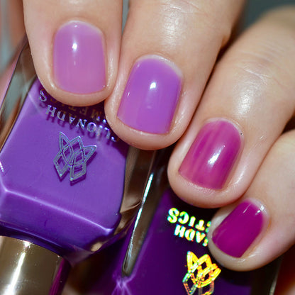 Close-up of nails painted with Cirrus and Euphoric Nail Lacquer on fair skin tone. Hand is holding polish bottle.