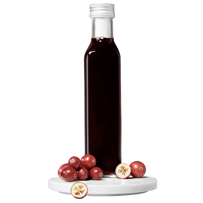 A bottle of Cranberry Balsamic Vinegar with fresh cranberries in front of it.