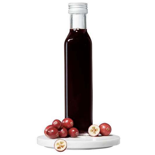 A bottle of Cranberry Balsamic Vinegar with fresh cranberries in front of it.