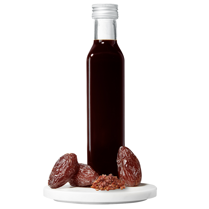 A bottle of Date Bacon Balsamic Vinegar with dates displayed in front.