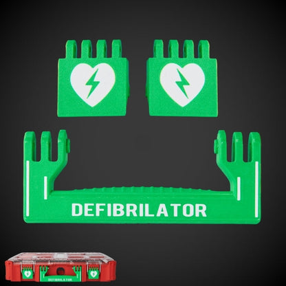 A set of green defibrillator components with white text and a heart symbol, including a handle and latches, with a red Milwaukee Packout container in the background.