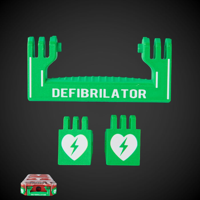 Green defibrillator kit components with white text and a heart symbol, including a handle and two latches, against a black background. The handle has 'DEFIBRILLATOR' text on it.
