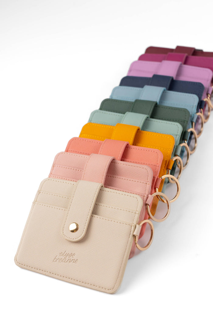 Row of colorful keychains attached to a beige cardholder on a white background