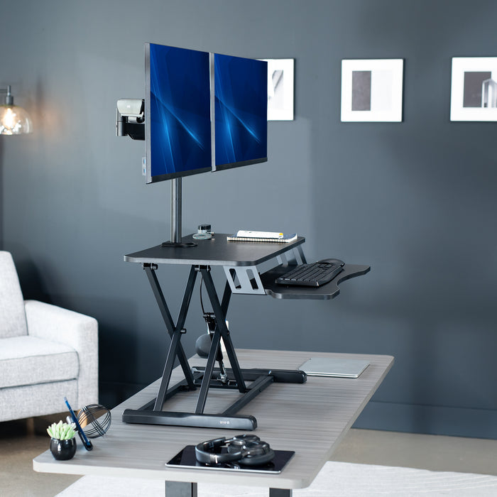 Height adjustable desk riser with articulating mechanical dual monitor mount.