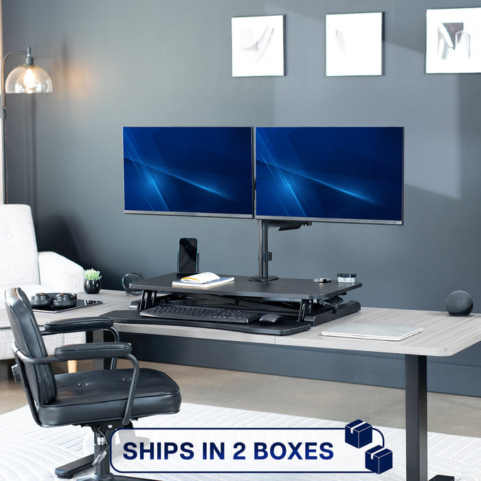 Height adjustable desk riser with articulating mechanical dual monitor mount.