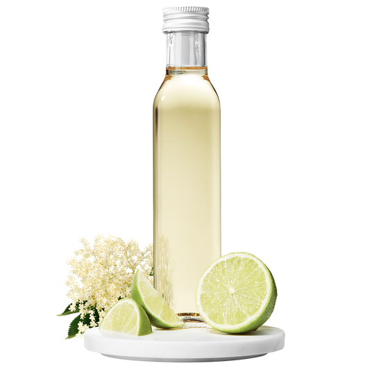 A bottle of Elderflower Apple Lime Vinegar with a cap, accompanied by elderflower blossoms and lime slices.