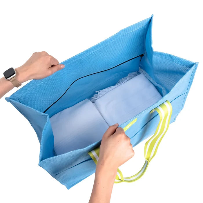 Blue mesh storage bag with white pillows inside, held open by hands on a white background