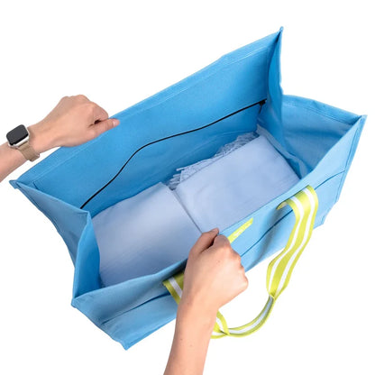 Blue mesh storage bag with white pillows inside, held open by hands on a white background